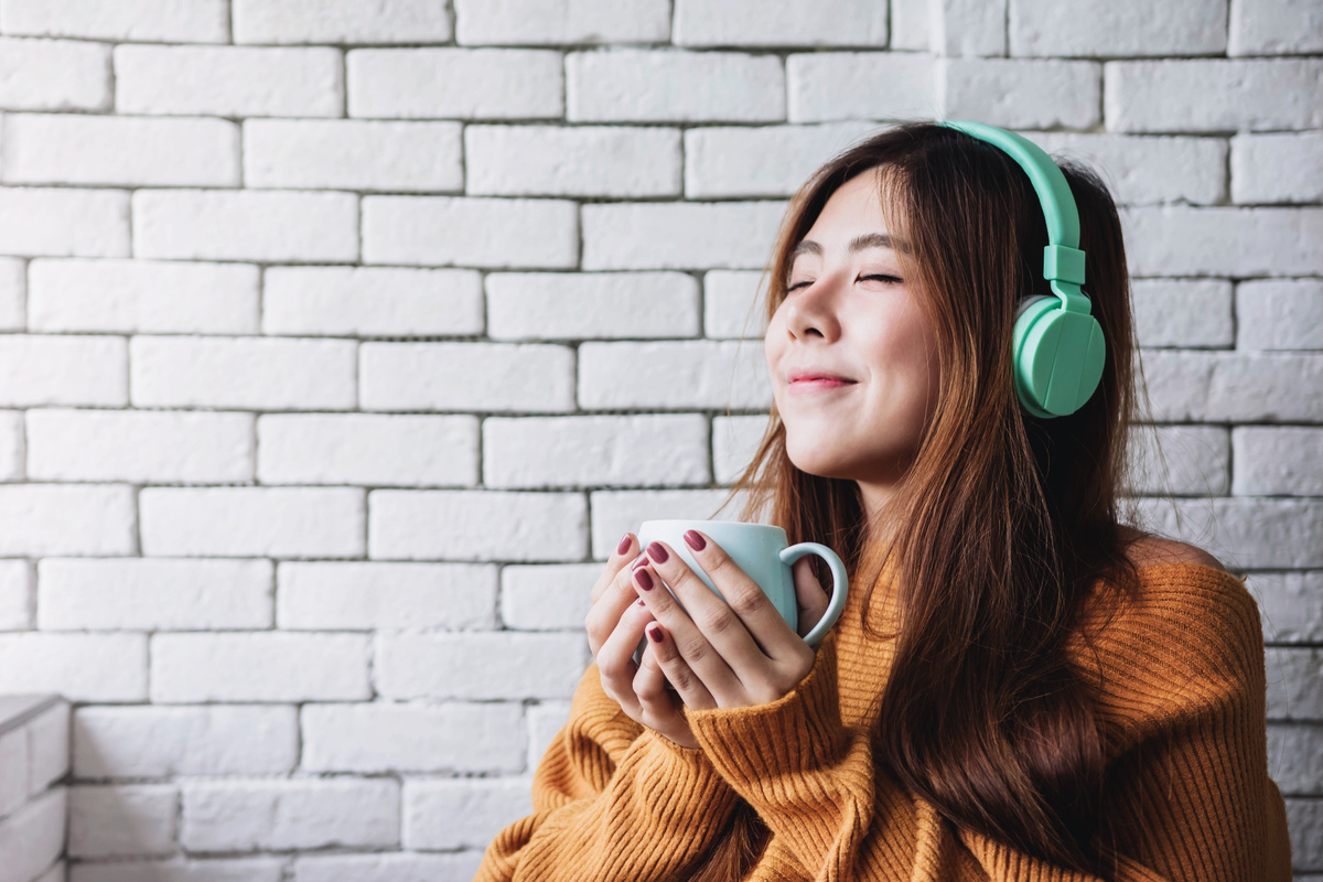 Woman Listening to Music on Headphones While Drinking Coffee